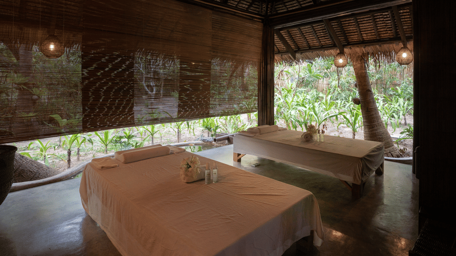 Open-air dining space with wooden furniture under a thatched roof at Flower Island Resort.