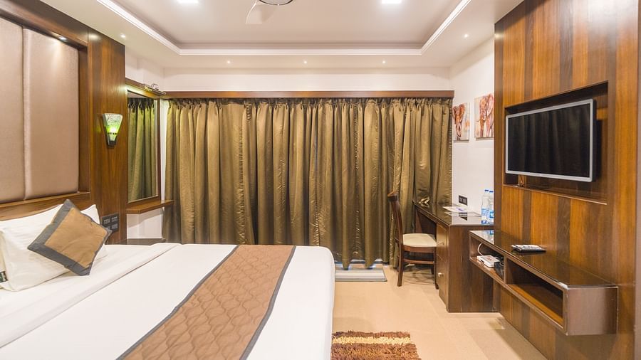 Side view of a room with a bed and a window on the side at Hotel Altitude, Madikeri.