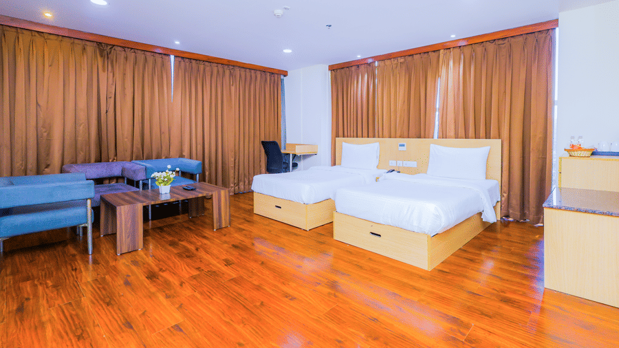 A spacious hotel room with 2 single beds, wooden flooring, and a comfortable seating area - Hyphen Business Hotel, Noida