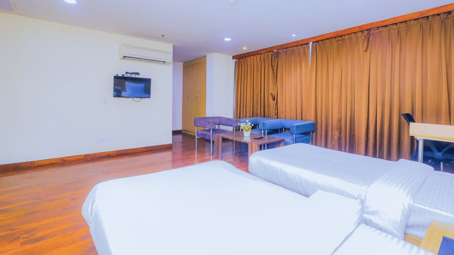 A bright hotel room with 2 single beds, a television, and light coloured curtains - Hyphen Business Hotel, Noida