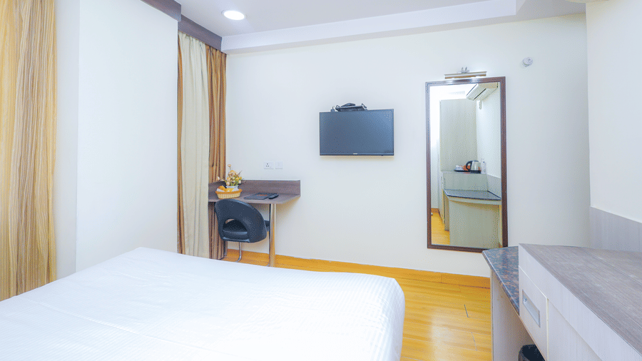 A well-appointed hotel room with a large bed, a desk, a mirror, and warm lighting - Hyphen Business Hotel, Noida