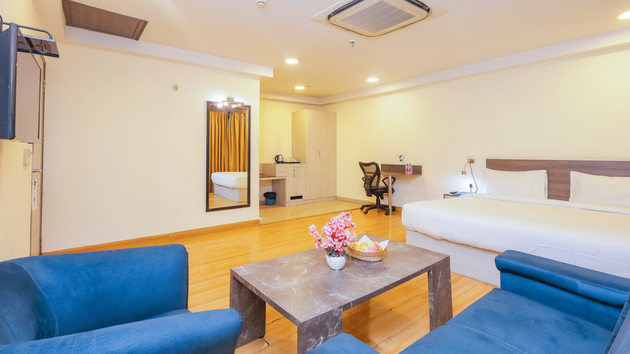 An expansive hotel room featuring a large bed, a comfortable seating area, and a television - Hyphen Business Hotel, Noida