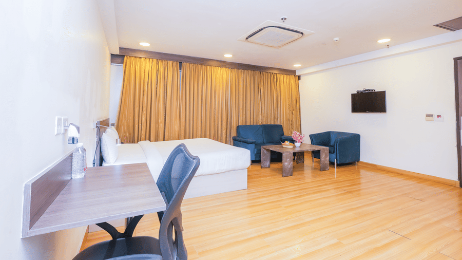 A comfortable hotel room featuring 2 single beds, a desk, and a blue armchair - Hyphen Business Hotel, Noida