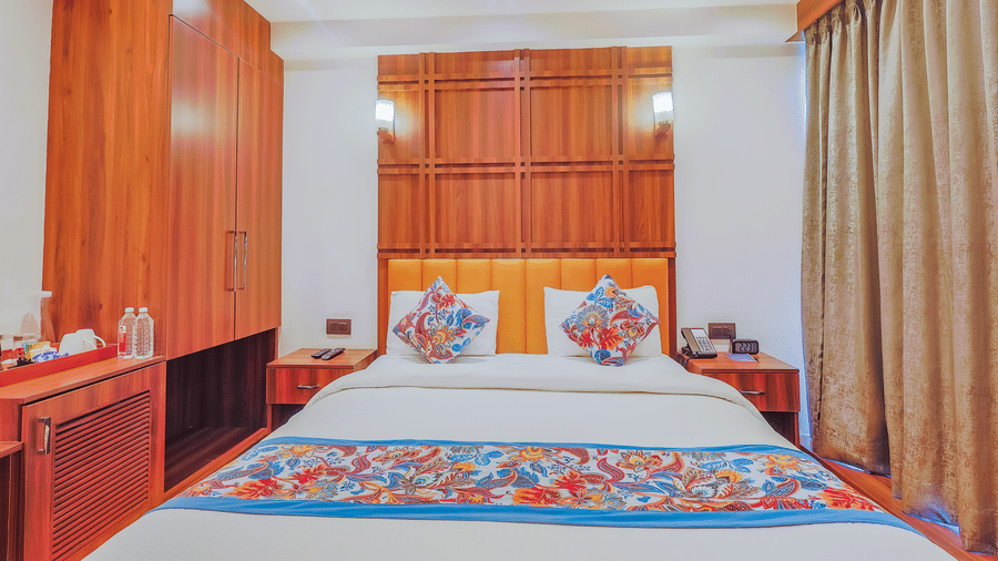 A well-decorated hotel room with a large bed, wooden furniture, and patterned bed linens - Hyphen Business Hotel, Noida