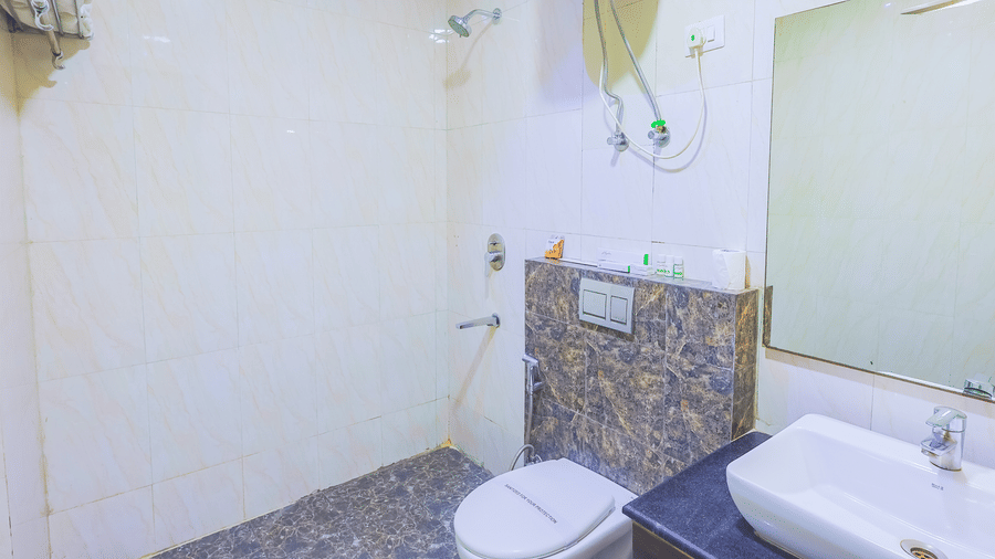 A compact and clean hotel bathroom with a white toilet, sink, and tiled walls - Hyphen Business Hotel, Noida