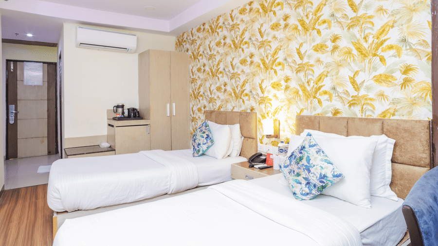 A bright hotel room featuring twin beds with white linen and decorative pillows - Hyphen Grand, Haridwar
