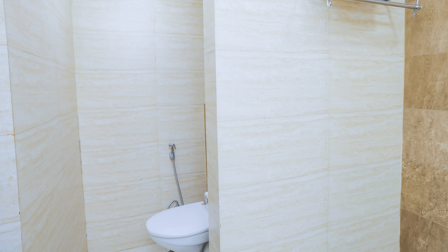 Minimalist bathroom corner with toilet and towel rack at Hyphen Premier Hotel, Meerut.