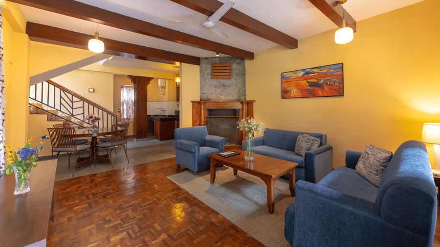 A large living room in a luxury villa featuring blue sofas, a fireplace, and exposed ceiling beams - Johnson Lodge & Spa, Manali