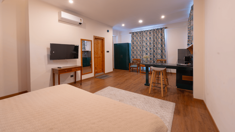 A comprehensive wide-angle shot of the studio interior showcasing the wooden floors and modern amenities - Johnson Lodge & Spa, Manali