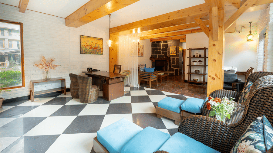 A bright, airy lobby featuring wooden beams, checker floors, and comfortable armchair seating - Johnson Lodge & Spa, Manali