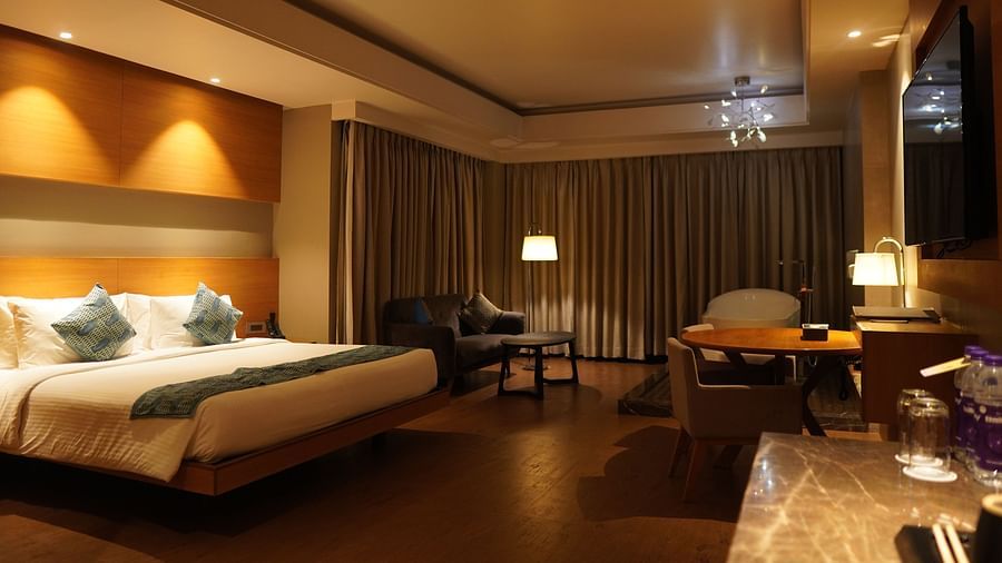 Spacious room with a large bed, cushioned furniture, and closed window curtains