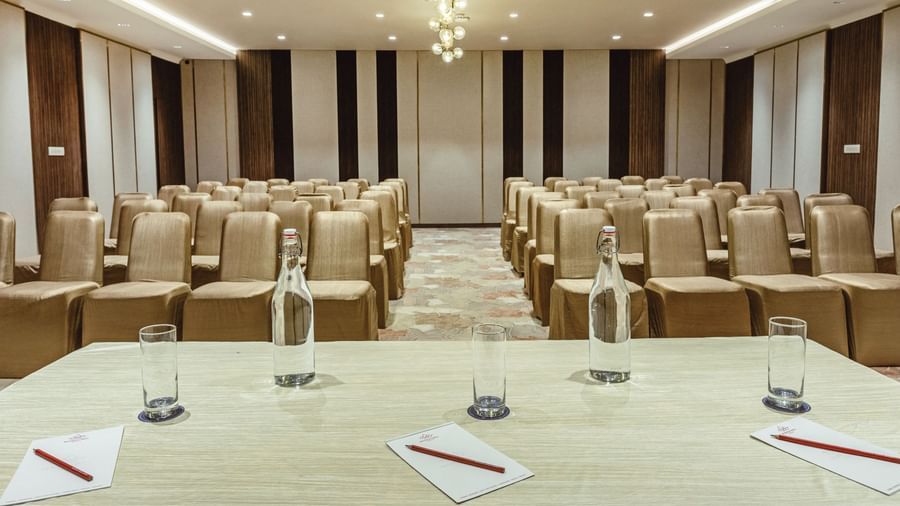 A hall at Mango Hill Central, Chennai, set up in a theatre style with rows of chairs facing a main table with glasses and water bottles.