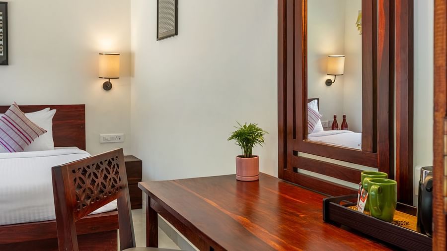 A close-up view of a wooden desk in a hotel room, featuring a mirror, a small potted plant, and two mugs on a tray - Mango Hill Resort, Coimbatore
