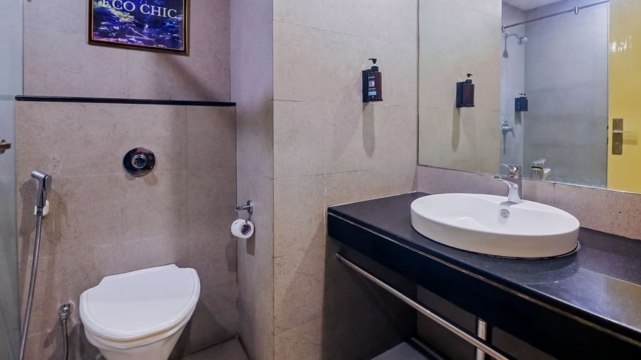 Modern washroom with mirror, sink, and shower at Max Hotel Prayagraj.