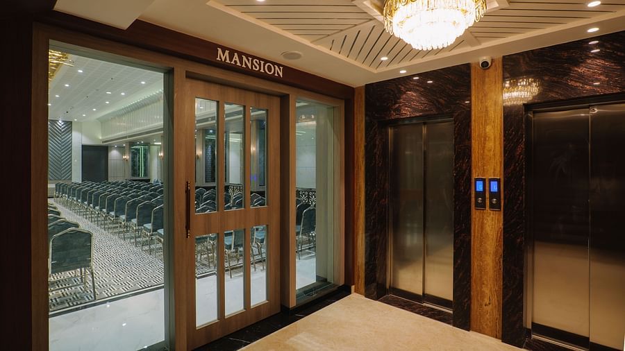 A brightly lit corner of a room shows large glass doors leading to another area - Melior Inn