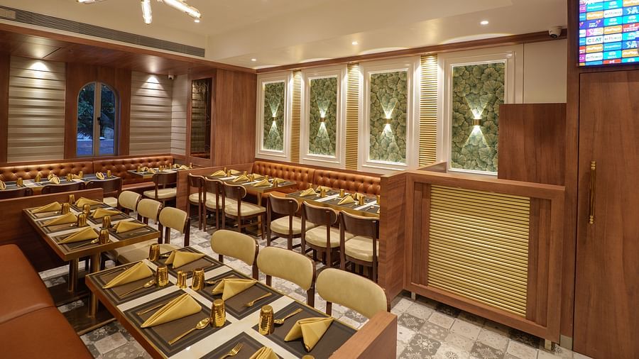 A well-lit restaurant displays set tables, wooden chairs, warm lighting, and decoration on the walls - Melior Inn