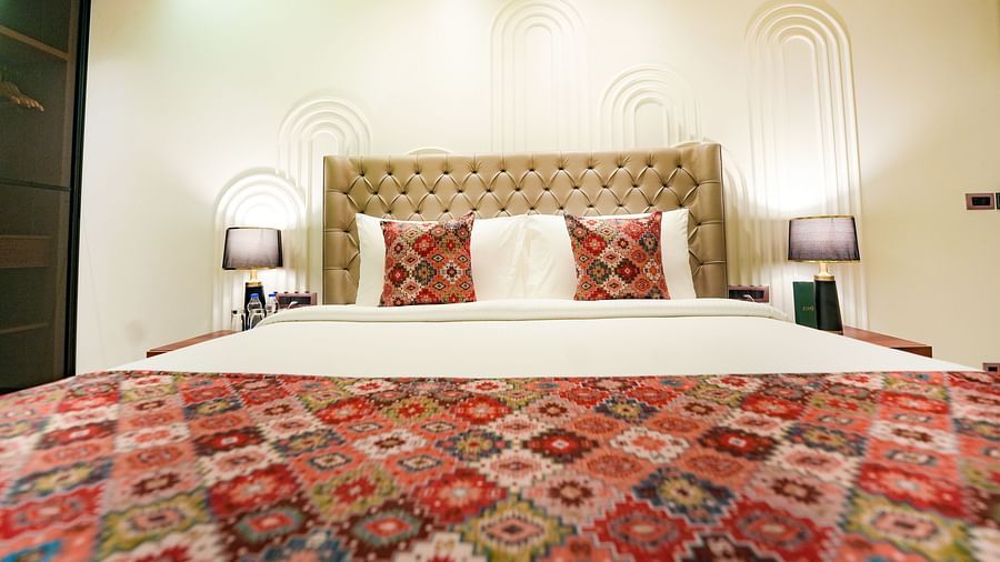 An image of a bed viewed from the foot, showcasing a headboard and two night lamps positioned on either side of the bed - NAMAMI BY ZENQ BANKHANDI
