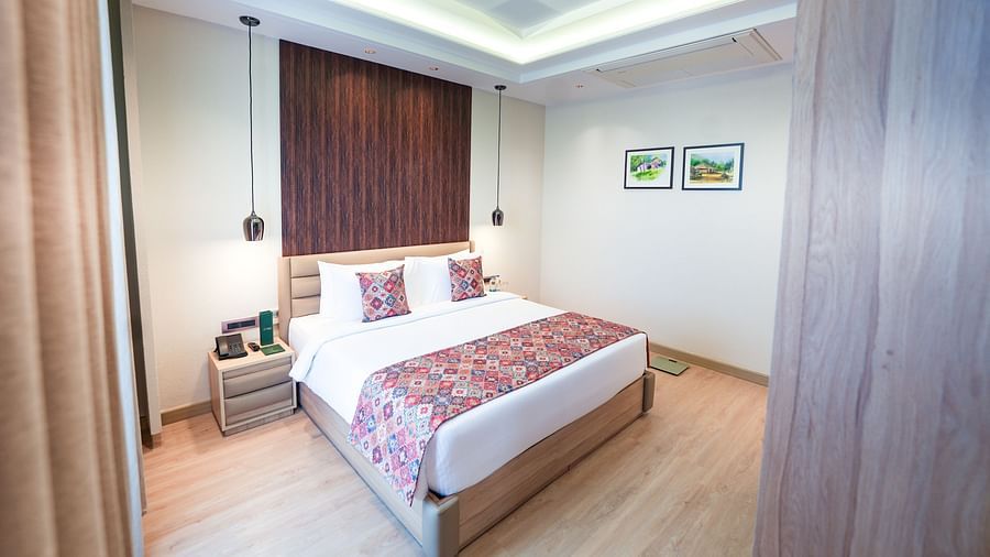 An image of a bed with a nightstand beside it, featuring hanging ceiling lamps that create a coy, warm lighting in the room - NAMAMI BY ZENQ BANKHANDI
