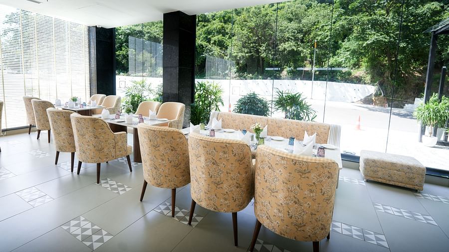 A hotel restaurant featuring a dining table arranged near a large client-facing window, offering a scenic view - NAMAMI BY ZENQ BANKHANDI