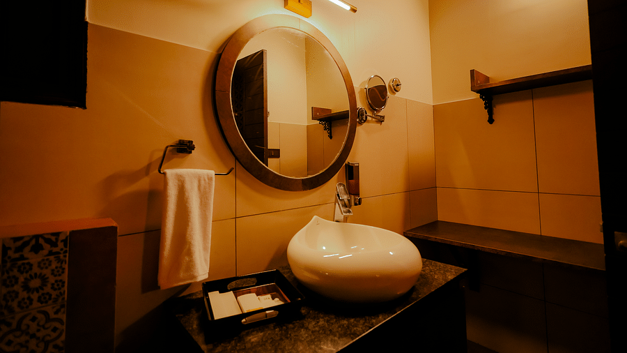 A modern bathroom with a round mirror and a white sink at Nirantara Resort & Spa