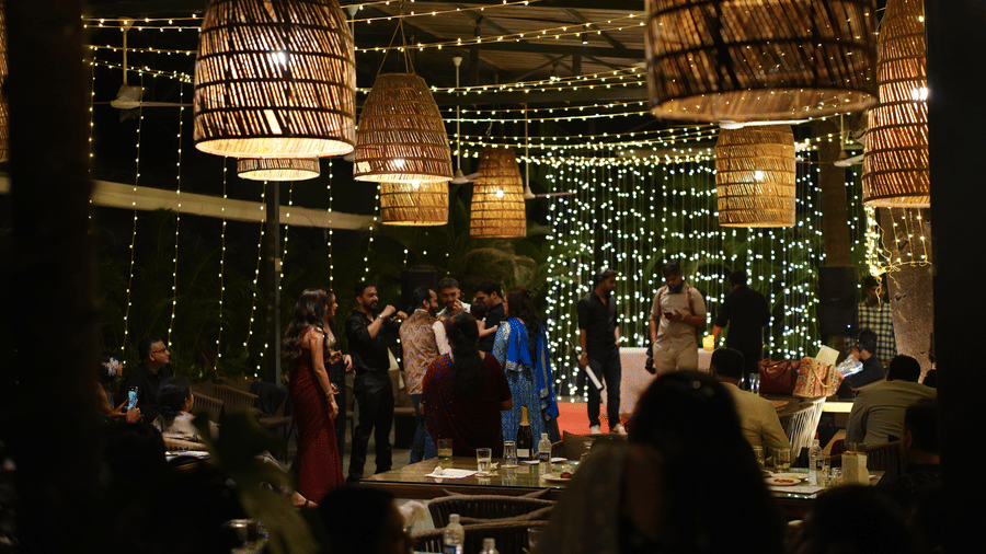 An outdoor event space at Oceanature Resort, Alibaug decorated with hanging woven lights and strings of fairy lights over people.