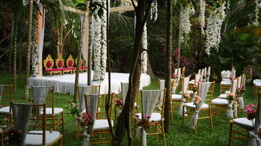 An outdoor lawn at Oceanature Resort, Alibaug arranged with guest chairs facing a decorated white wedding stage setup.