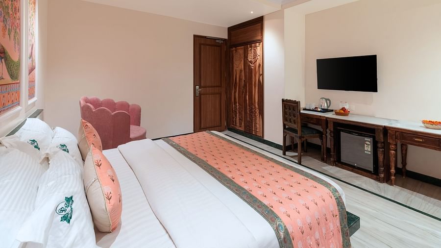 A spacious bedroom view from the headboard at Panna Vilas Palace, showcasing a wall-mounted television with a wooden table positioned below it | Panna Vilas Udaipur
