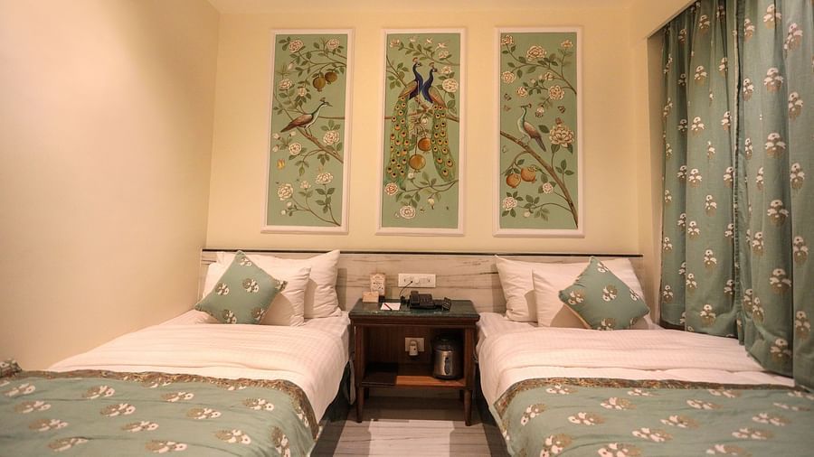Twin beds placed side by side with a wooden bedside table in the middle, and there are three photo frames positioned above the headboard | Panna Vilas Udaipur