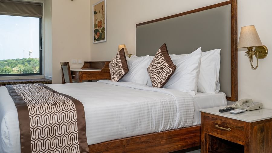 Comfortable double bed setup complemented with wooden furniture - Rajbagh Wellness, Udaipur