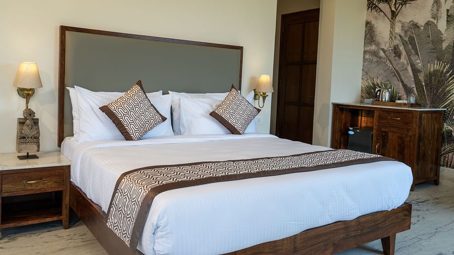 Stylish bedroom showcasing luxury finishes and a cosy corner sitting area - Rajbagh Wellness, Udaipur