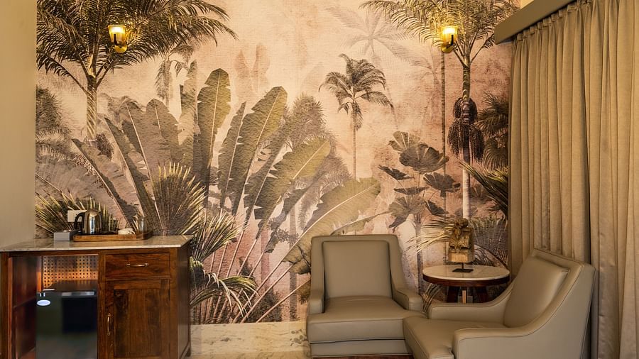 A vibrant bedroom with a tropical mural, seating space, and warm lighting - Rajbagh Wellness, Udaipur