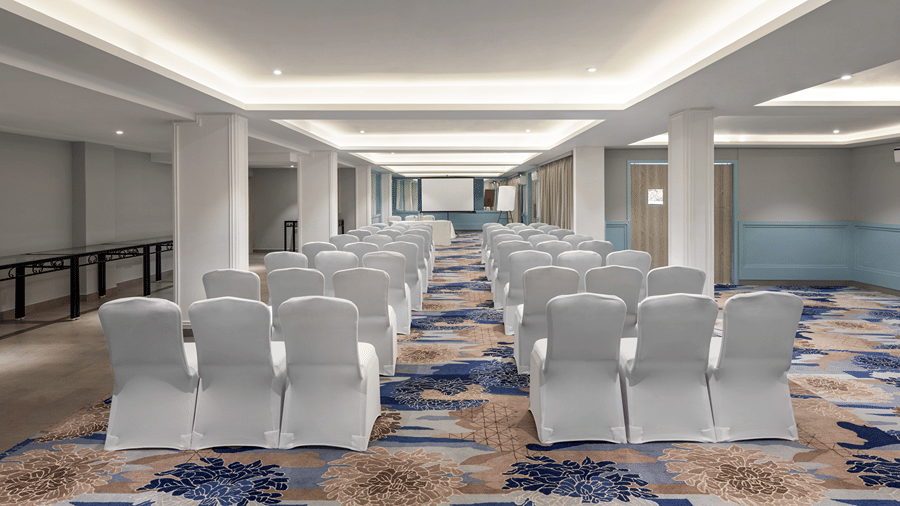Spacious meeting room arranged with rows of chairs and a presentation screen.