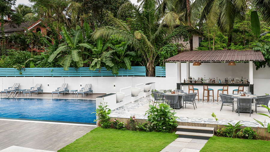 Outdoor pool area surrounded by lush tropical greenery and landscaped lawns.