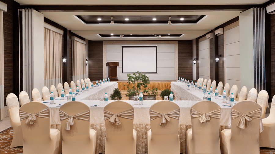 A large conference room featuring a long u-shaped table set with chairs and place settings at Ramada by Wyndham Mussoorie Mall Road