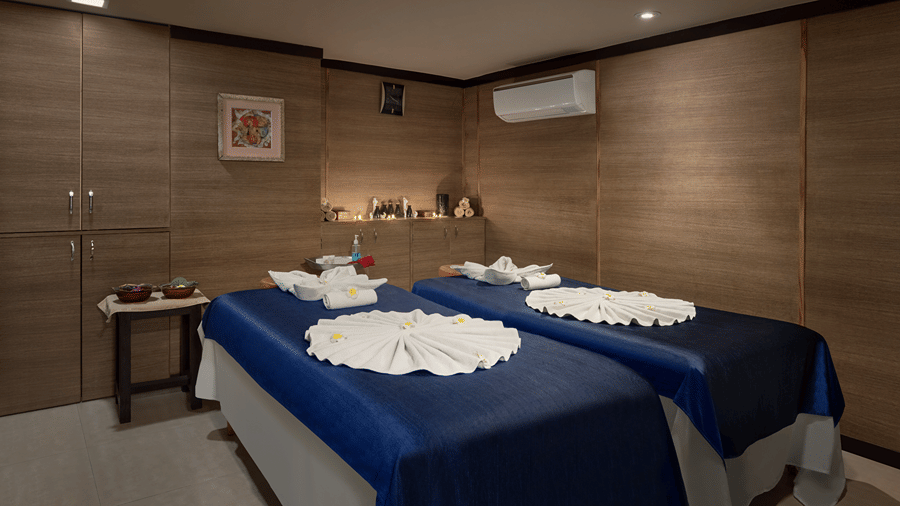A spa treatment room with 2 massage tables topped with blue linens at Ramada by Wyndham Mussoorie Mall Road.