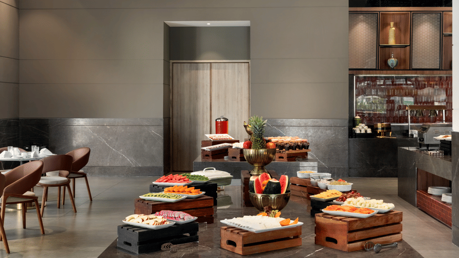 Buffet spread area with dark grey walls, vibrant food displays, and wooden serving counters at the hotel restaurant.