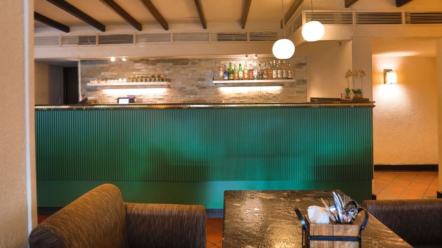 A cosy bar at Shilton International, Kochi, with a well-stocked counter and comfortable seating, ideal for relaxation.