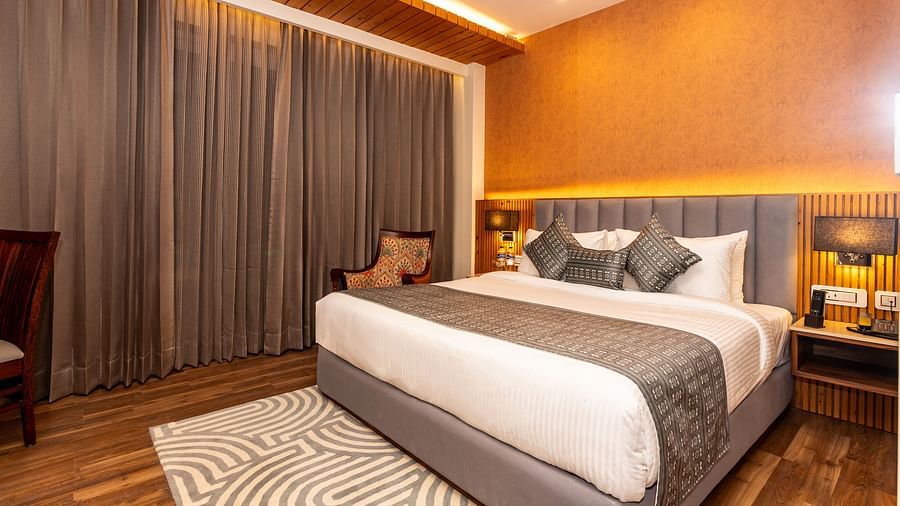 An image of a Deluxe Room with a bed, bed side table, lamps, and rug - The Belvedere Himalayan Retreat, McLeodganj