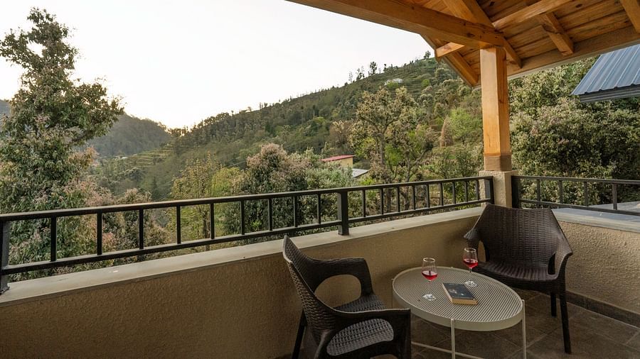 Balcony with outdoor seating and a small round table in the middle, overlooking a scenic mountain view at The Chamomile Estate.