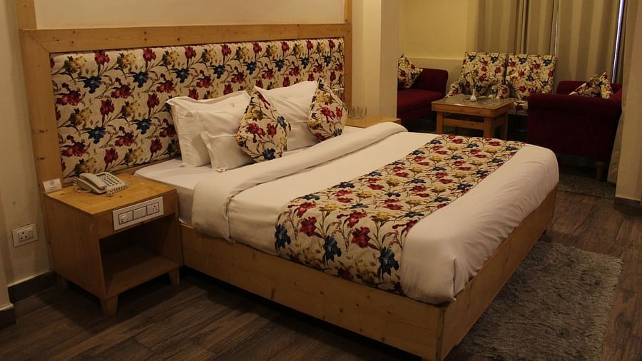 A well-furnished bedroom with floral headboards, warm lighting, and comfortable bedding at Dagshai Manor Kasauli - Inde Hotels.