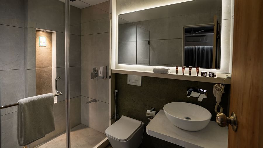 A shot of a well equipped bathroom featuring a expansive mirror and a shower segment.