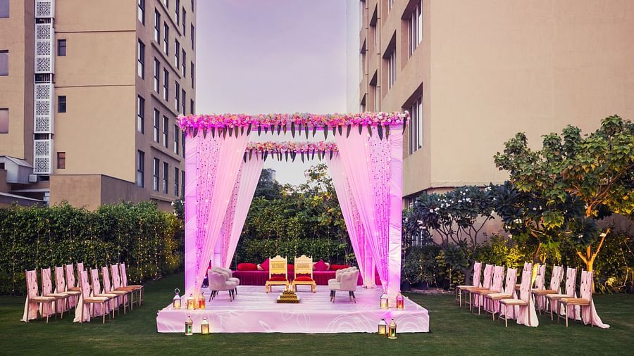 a stage set with two chairs and a canopy above and a group of chairs lined up on either side of the stage - The Hideaway Banquets & Lawns, Greater Noida