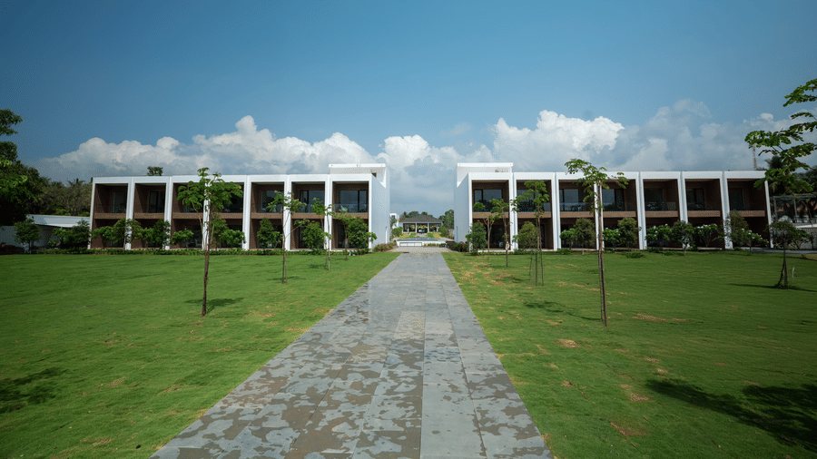  A lush green lawn at The Shore Trishvam, Pondicherry divided by a pathway in the middle with a clear blue sky in the background.