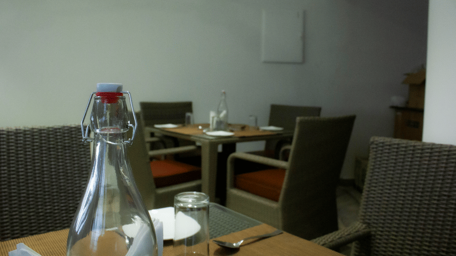 Side view of the Spice and Slice Restaurant at WOW Naturefull Resorts, Yercaud, overlooking other dining dining tables lined with table mats and plates.