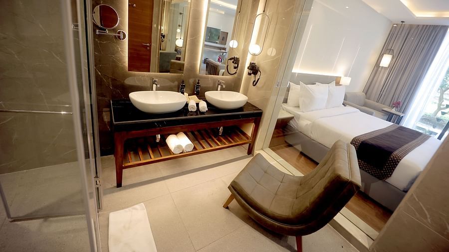 Modern bathroom with dual basins, a vanity mirror, and a view into the bedroom area at Wyndham Garden.