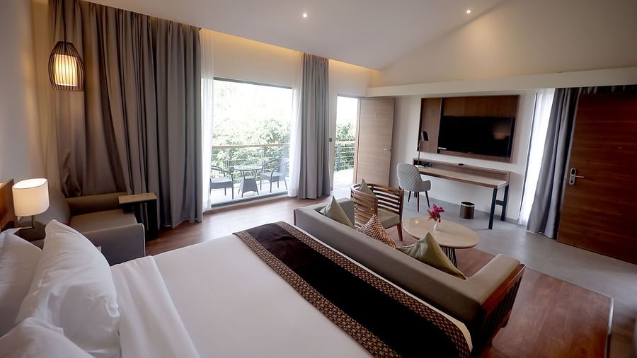 Spacious room with king-sized bed, sofa seating, and large window offering a garden view at Wyndham Garden.