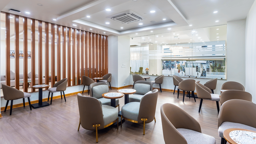 Modern seating area at L Cafe in Mandala Norling Lords Prime Kathmandu, featuring wooden slat partitions and circular tables.