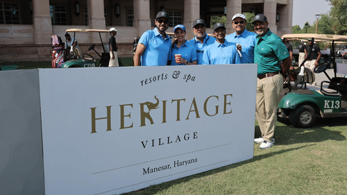 Participants posing near the Heritage Village branding board at an exclusive golf tournament.