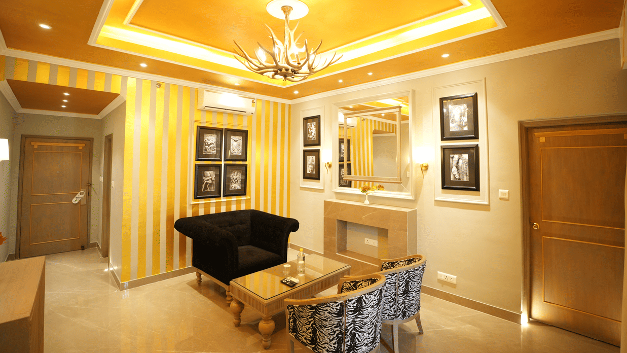 An Executive Suite lounge area at Clarks Khajuraho featuring a seating arrangement, a wall mirror, decorative panels, and an entry door.