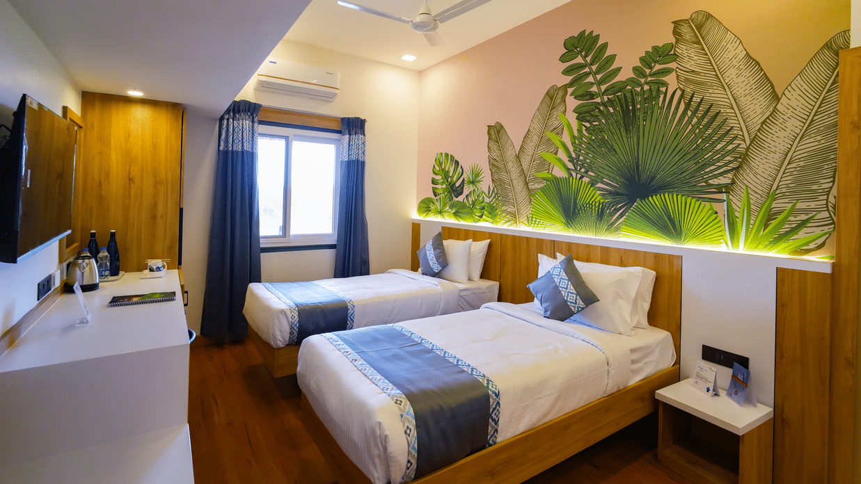 A view of the deluxe twin room showing two beds and a feature wall with a bright, leafy design.